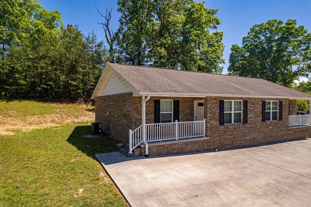 single story home with roof with shingles, a front lawn, brick siding, central air condition unit, and covered porch