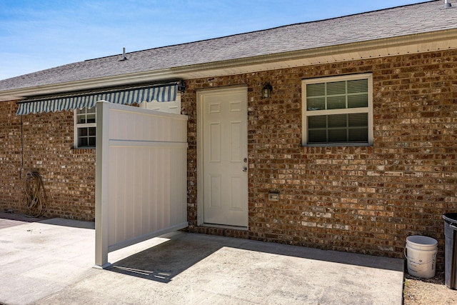 doorway to property featuring brick siding and a patio area