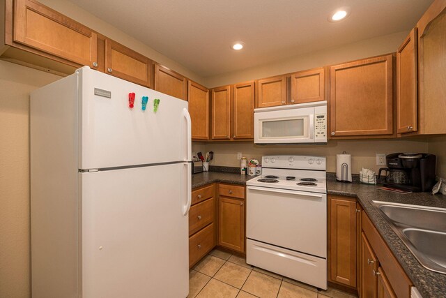 kitchen with white appliances, brown cabinets, and a sink