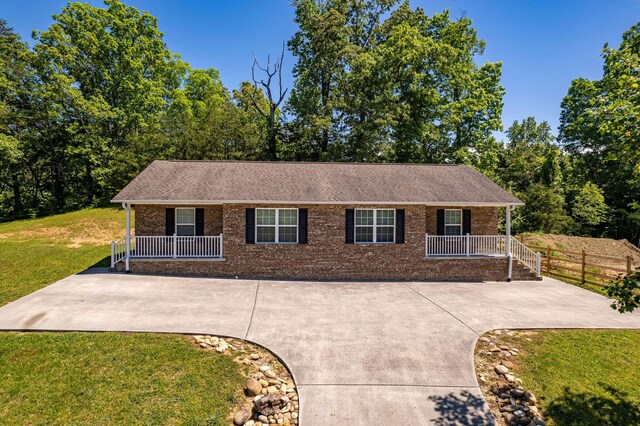 ranch-style house featuring brick siding, fence, covered porch, and a front yard
