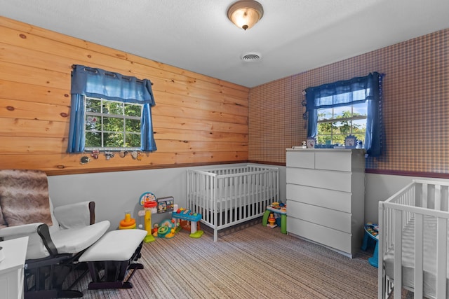 carpeted bedroom with visible vents and a crib