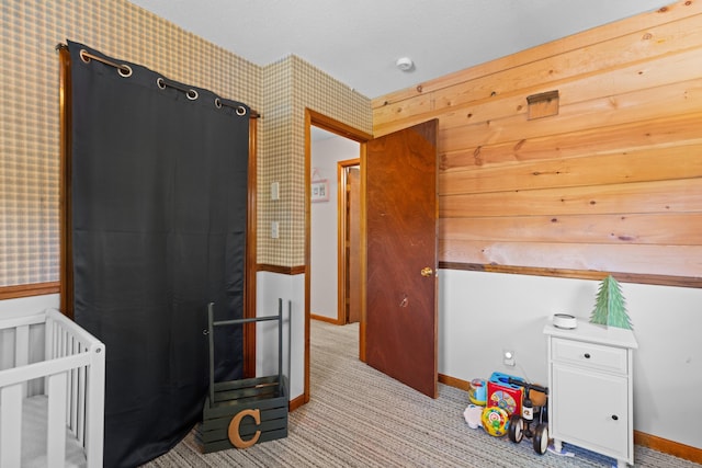 carpeted bedroom featuring wallpapered walls, a crib, and baseboards