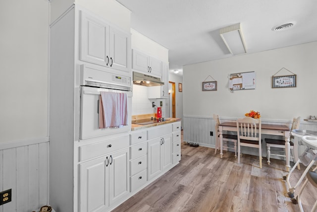 kitchen with under cabinet range hood, wainscoting, oven, and black electric stovetop