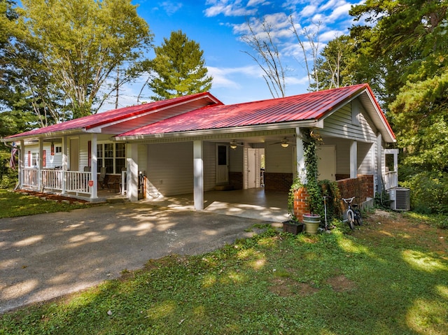 view of front facade featuring a porch, central air condition unit, driveway, and metal roof