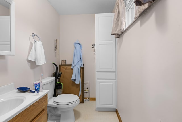 bathroom featuring baseboards, toilet, and vanity