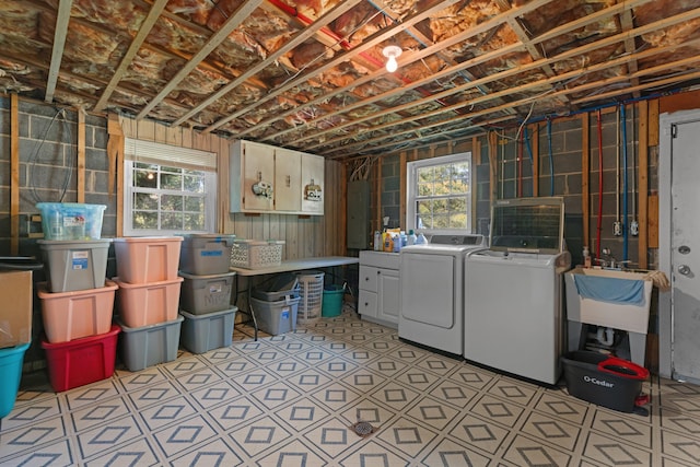 below grade area featuring washing machine and clothes dryer, a wealth of natural light, electric panel, and a sink