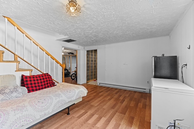 interior space with white fridge, a textured ceiling, wood finished floors, and a baseboard radiator