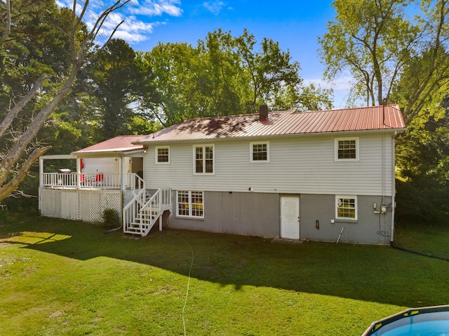 back of property with a wooden deck, stairs, a chimney, metal roof, and a yard