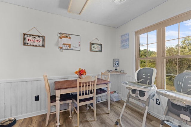 dining space with wood finished floors and wainscoting