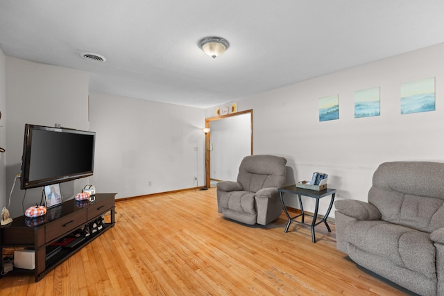 living room with wood finished floors, visible vents, and baseboards