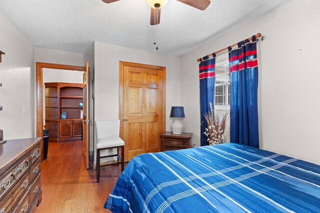 bedroom featuring a walk in closet, a textured ceiling, ceiling fan, dark hardwood / wood-style floors, and a closet