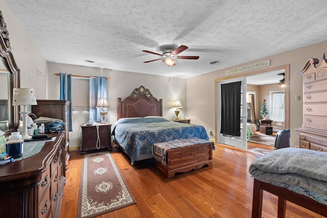 bedroom with ceiling fan, wood-type flooring, and a textured ceiling