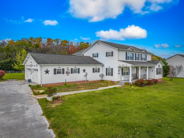 view of front of property with a garage, covered porch, and a front lawn