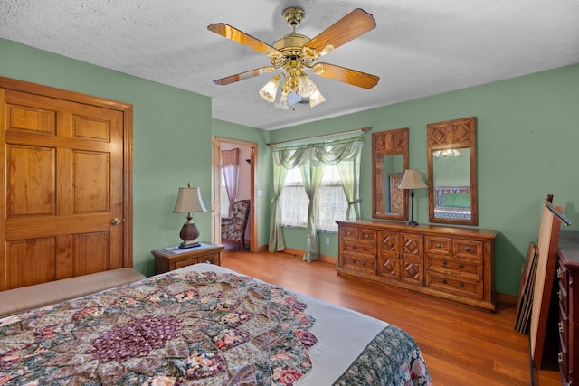 bedroom with ceiling fan, a textured ceiling, and light hardwood / wood-style flooring