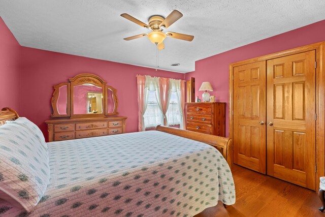 bedroom featuring ceiling fan, light wood-type flooring, a textured ceiling, and a closet