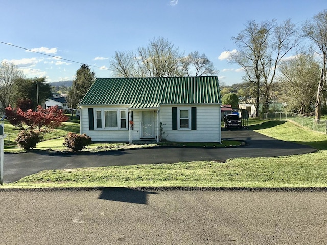 view of front of house featuring metal roof, a front yard, and fence