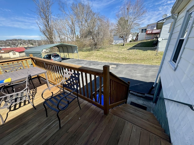 deck with a carport, a yard, and fence