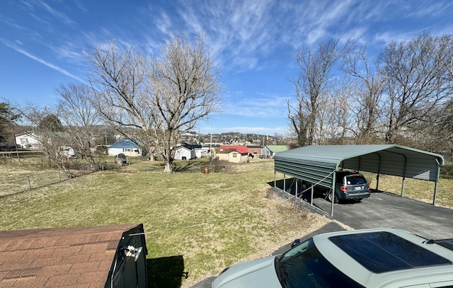 view of vehicle parking featuring a carport, a residential view, fence, and driveway