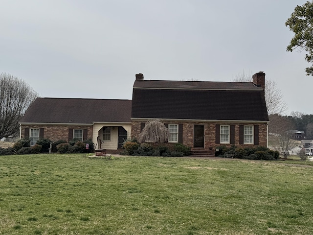 dutch colonial with brick siding, a gambrel roof, a front yard, and a chimney