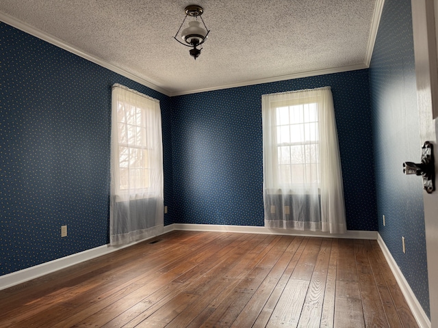 unfurnished room with a healthy amount of sunlight, wallpapered walls, ornamental molding, hardwood / wood-style flooring, and a textured ceiling