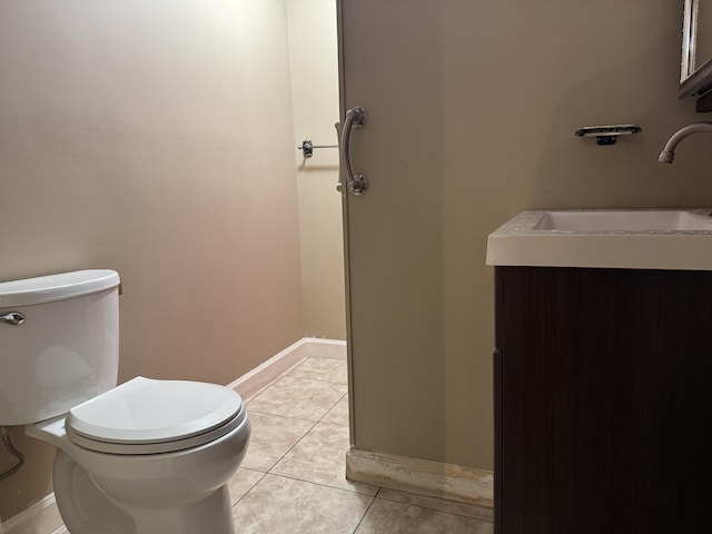 half bath featuring tile patterned floors, toilet, baseboards, and a sink