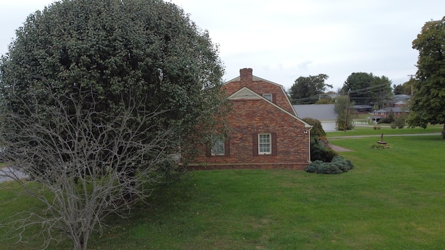 view of property exterior featuring a yard, brick siding, and a chimney