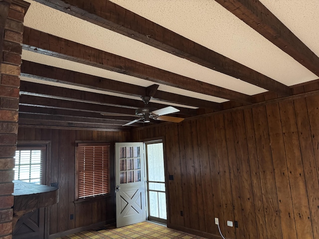 empty room featuring tile patterned floors, beamed ceiling, and wood walls