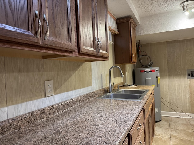 kitchen featuring light tile patterned floors, electric water heater, a textured wall, and a sink