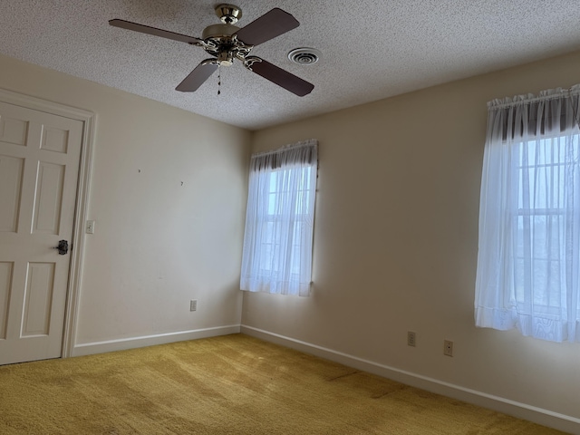 spare room with light colored carpet, a healthy amount of sunlight, ceiling fan, and a textured ceiling