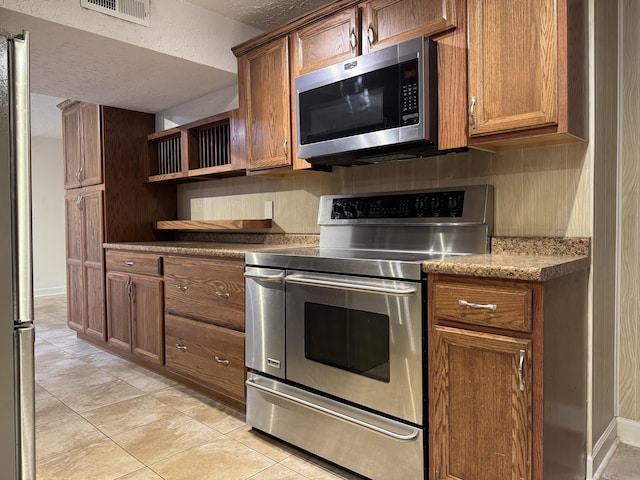 kitchen featuring visible vents, open shelves, decorative backsplash, appliances with stainless steel finishes, and brown cabinets