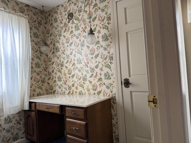 office featuring wallpapered walls and a textured ceiling