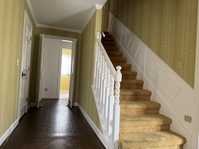 staircase with wallpapered walls, crown molding, baseboards, tile patterned floors, and a textured ceiling