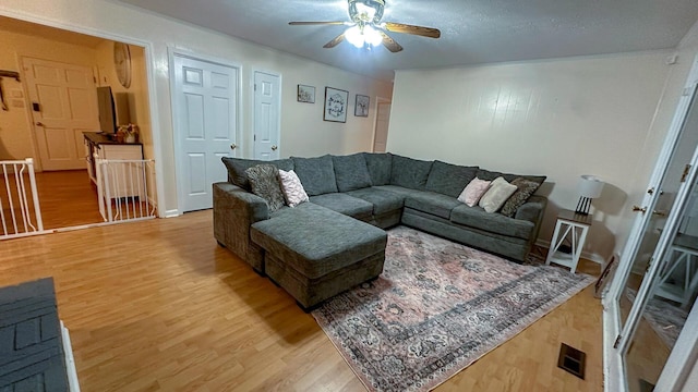 living room with hardwood / wood-style flooring, ceiling fan, and a textured ceiling