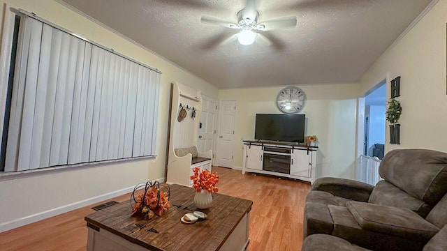 living room featuring ceiling fan, light hardwood / wood-style flooring, and a textured ceiling