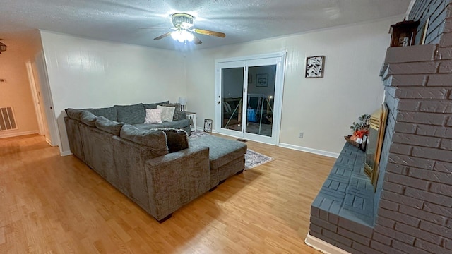 living room featuring ceiling fan, a textured ceiling, and light wood-type flooring