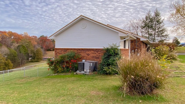 view of side of property with a yard and central AC unit