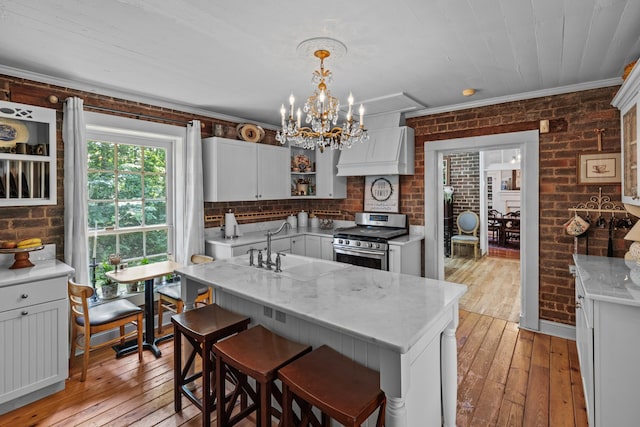 1130 Squirewood Way, Dandridge, TN 37725 - kitchen with stainless steel gas range oven, brick wall, a sink, a chandelier, and light wood finished floors