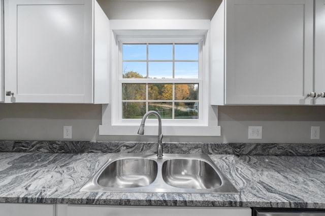 kitchen featuring white cabinetry, dark stone counters, and sink