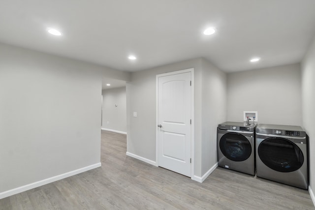 laundry area featuring washer and dryer and light hardwood / wood-style flooring