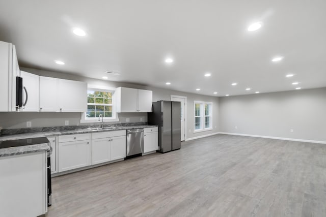 kitchen featuring white cabinetry, sink, light stone counters, light hardwood / wood-style floors, and appliances with stainless steel finishes