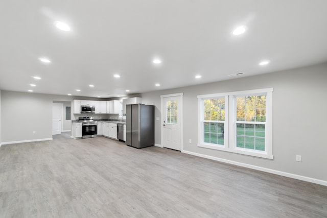 kitchen with white cabinets, sink, appliances with stainless steel finishes, and light hardwood / wood-style flooring