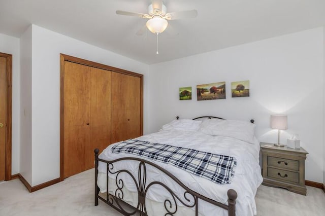 bedroom with ceiling fan, baseboards, a closet, and light colored carpet