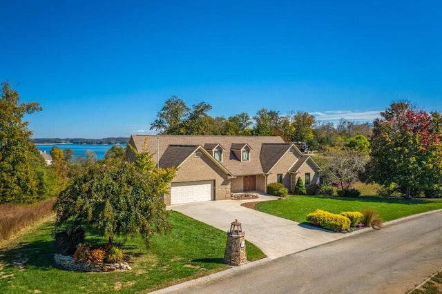 view of front facade featuring concrete driveway, a water view, an attached garage, and a front lawn