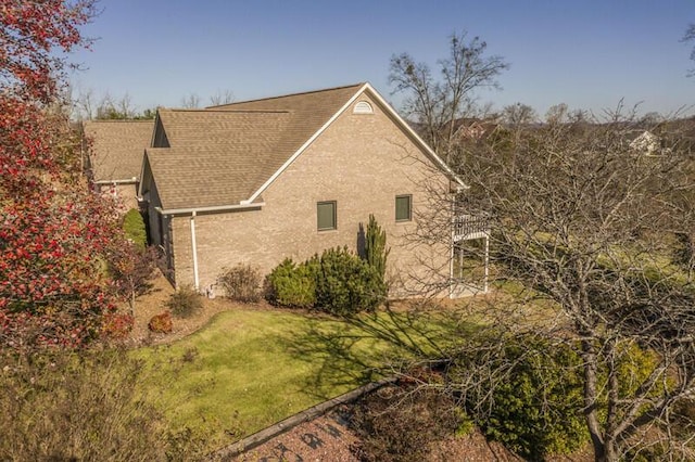 view of side of home with a shingled roof and a yard