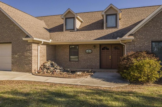 view of front of house featuring a garage, brick siding, and roof with shingles