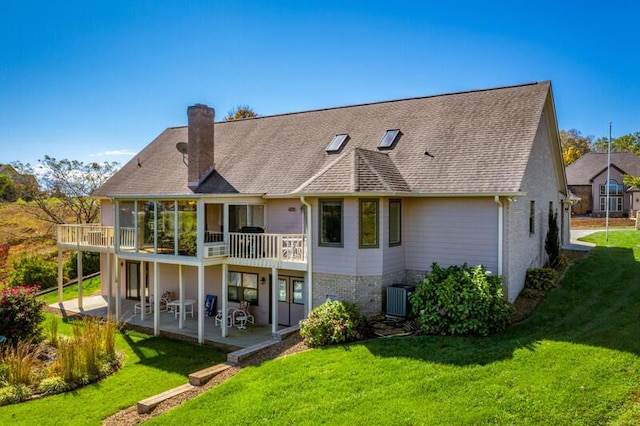 back of property with a yard, brick siding, a chimney, and a patio area