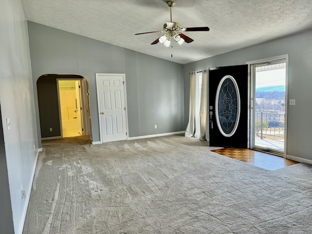 carpeted foyer entrance with ceiling fan, vaulted ceiling, and a textured ceiling