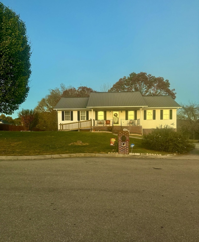 ranch-style home featuring covered porch and a front lawn