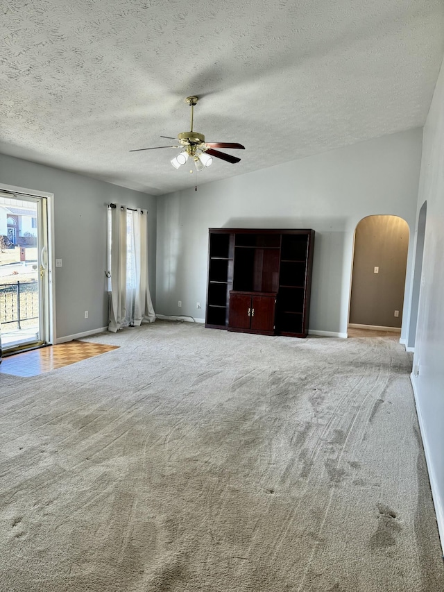 unfurnished living room featuring a textured ceiling, light colored carpet, and ceiling fan