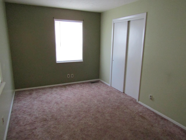 unfurnished bedroom featuring carpet, a closet, and baseboards
